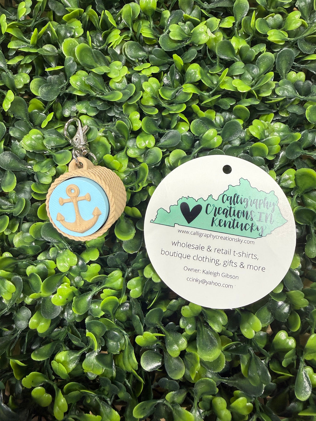 Blue anchor keychain on a green leafy background