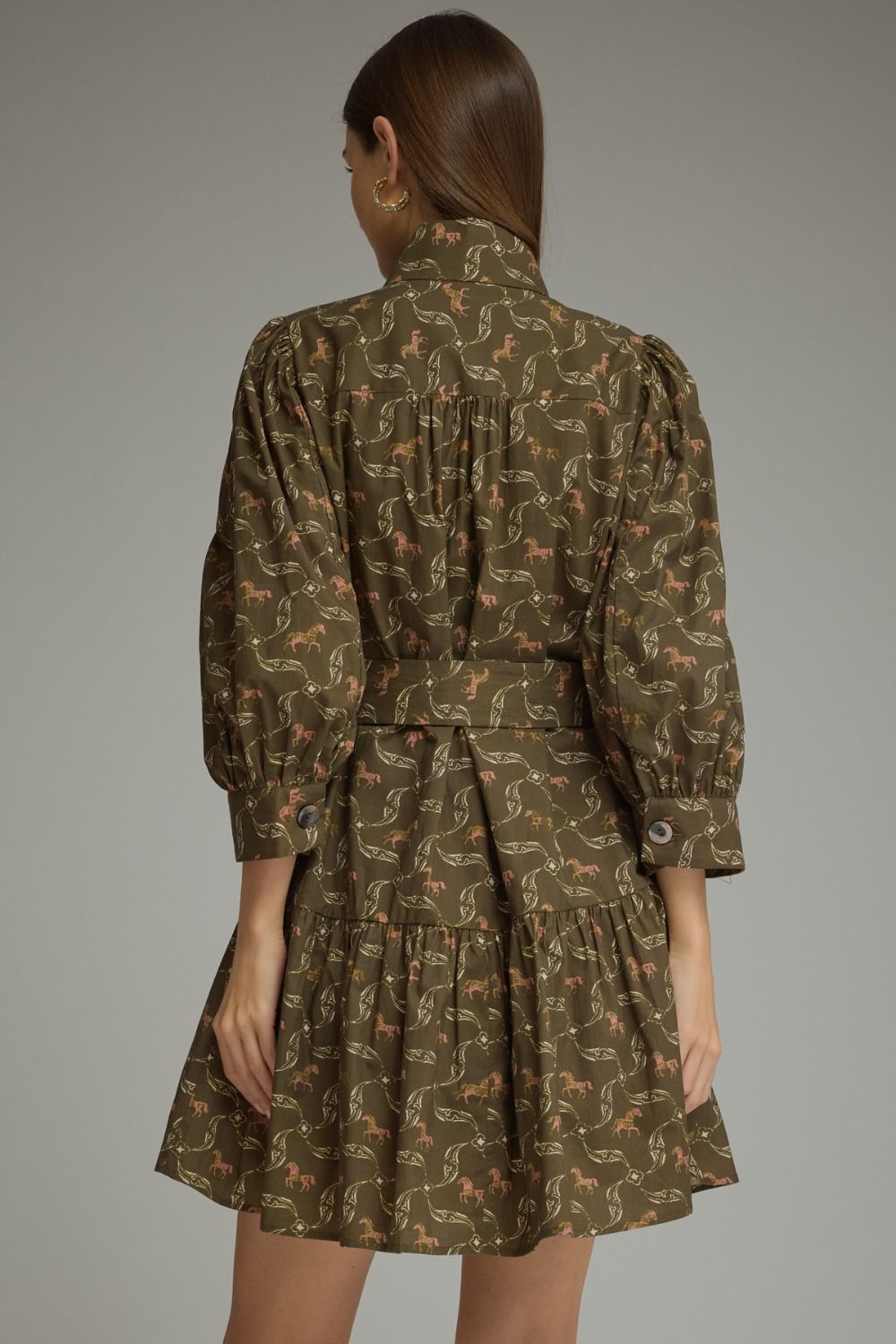 Entro-Horse print ¾ puff sleeve mini dress with a shirt collar and button closure at front. Self-tie belt at waist. Button cuffs. Tiered skirt. Side pockets.