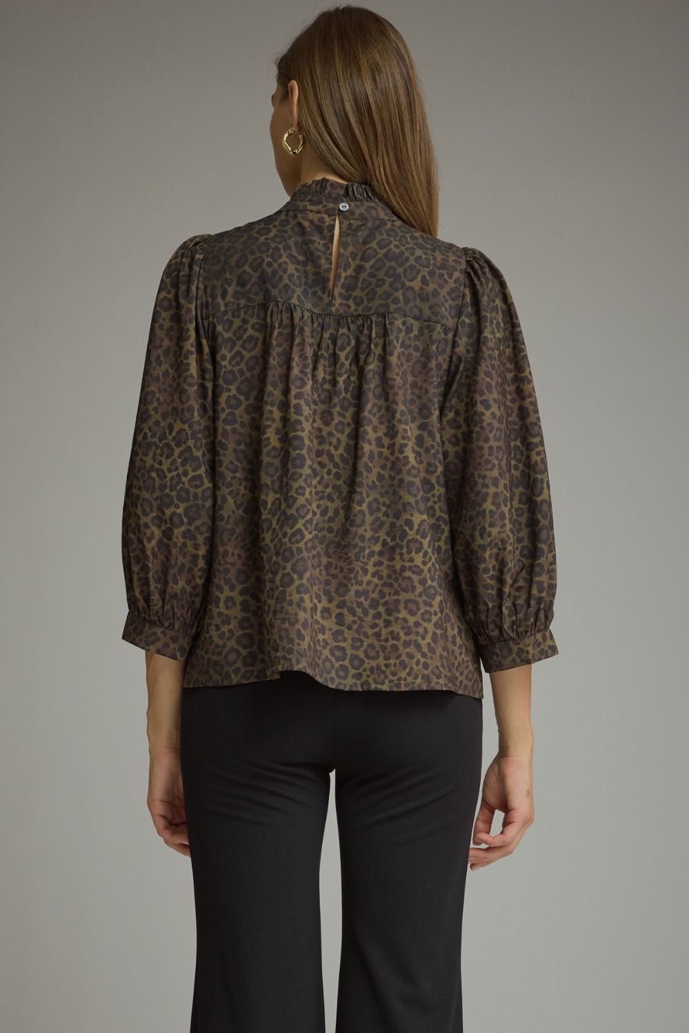 Entro-Animal print ¾ balloon sleeve top with a ruffle stand collar. Ruffle trim detail at front. Back keyhole with button closure. Gathered detail at back.
