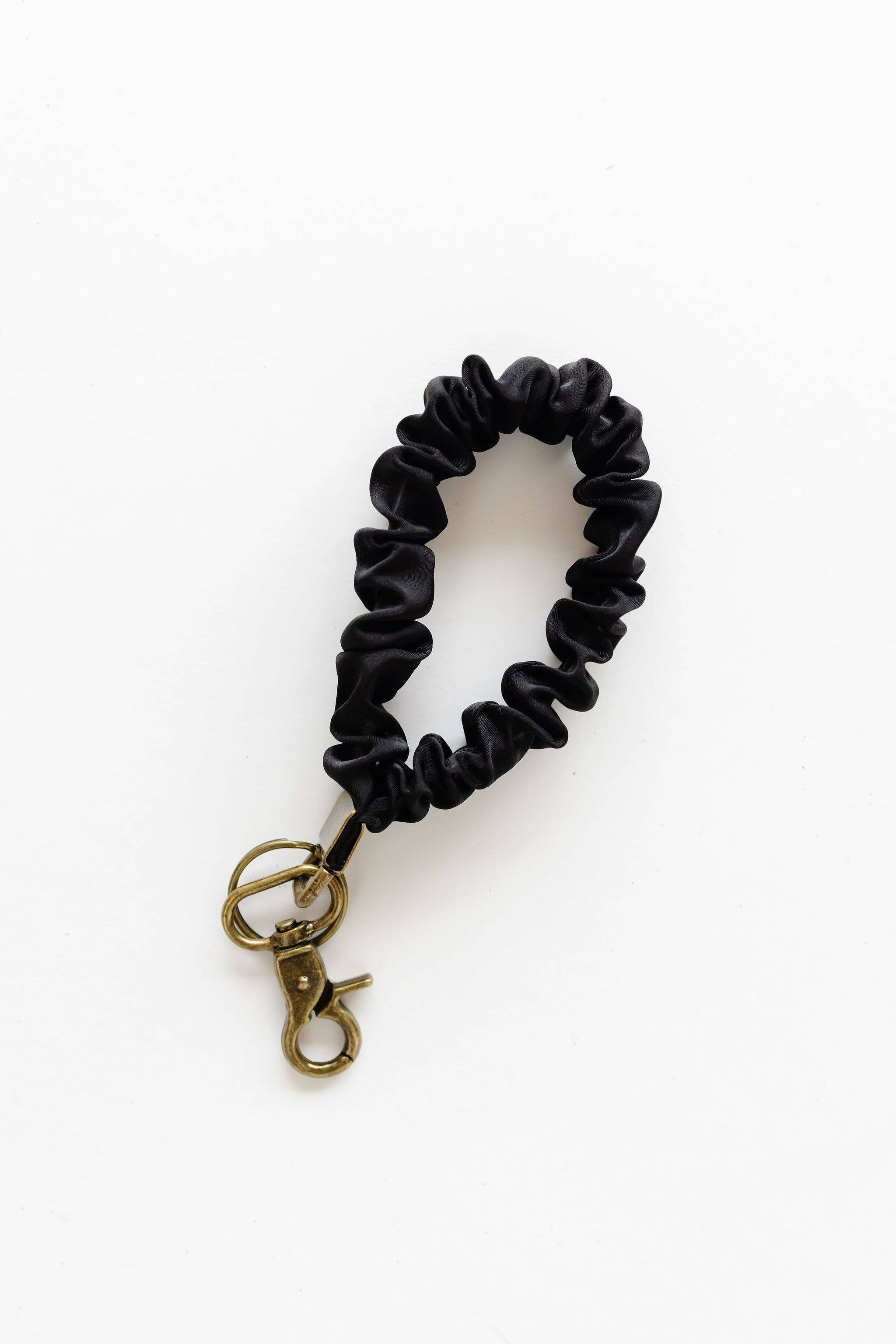 Black scrunchie with gold clasp on a white background
