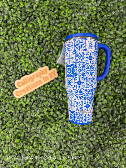 Blue and white patterned tumbler with a blue handle on a green textured background, with 'Calligraphy Creations In Kentucky' branding.
