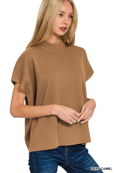 A woman wearing a camel brown ribbed knit short-sleeve top with a mock neck, paired with blue jeans, against a plain white background.