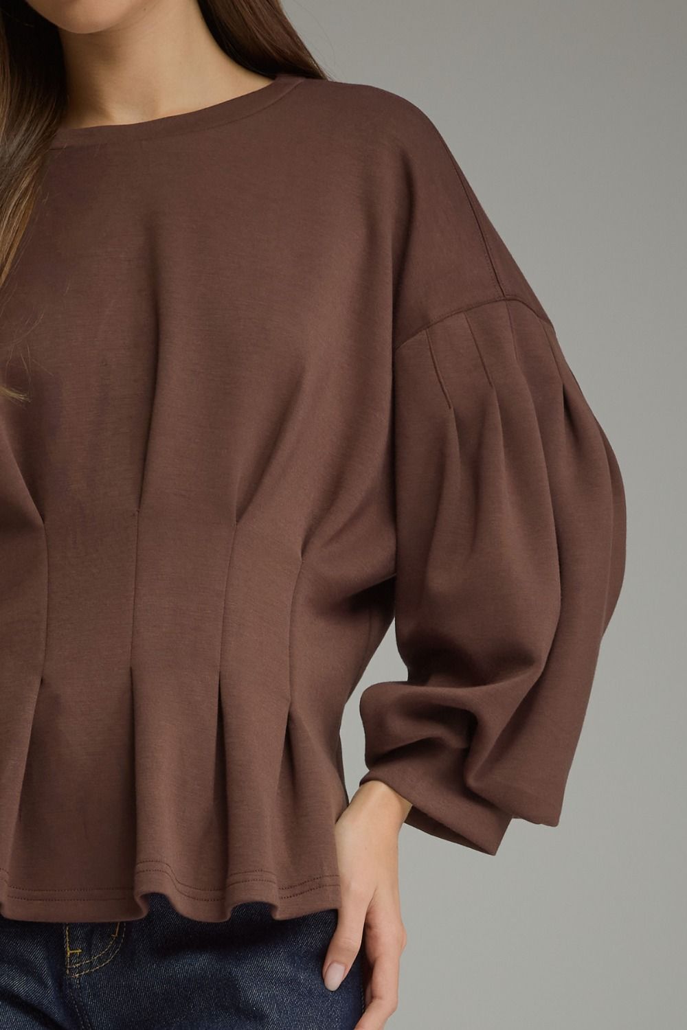 Entro-Solid long balloon sleeve top with a round neckline and pleated detail at waist.