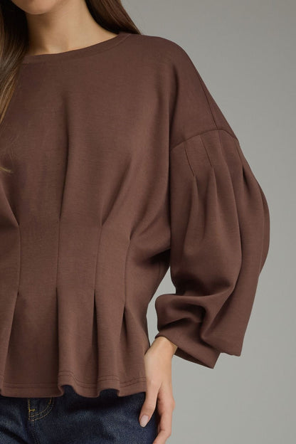 Entro-Solid long balloon sleeve top with a round neckline and pleated detail at waist.