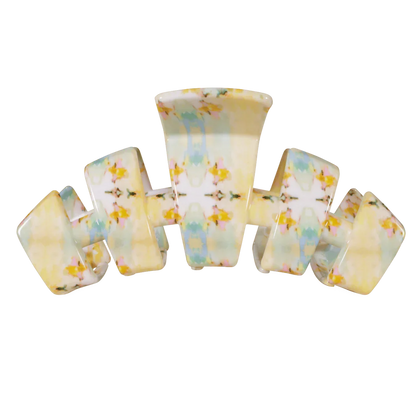 A vintage-style plastic claw hair clip with a marbled pattern of pale yellow, white, light blue, and small yellow floral accents, shown on a plain white background.