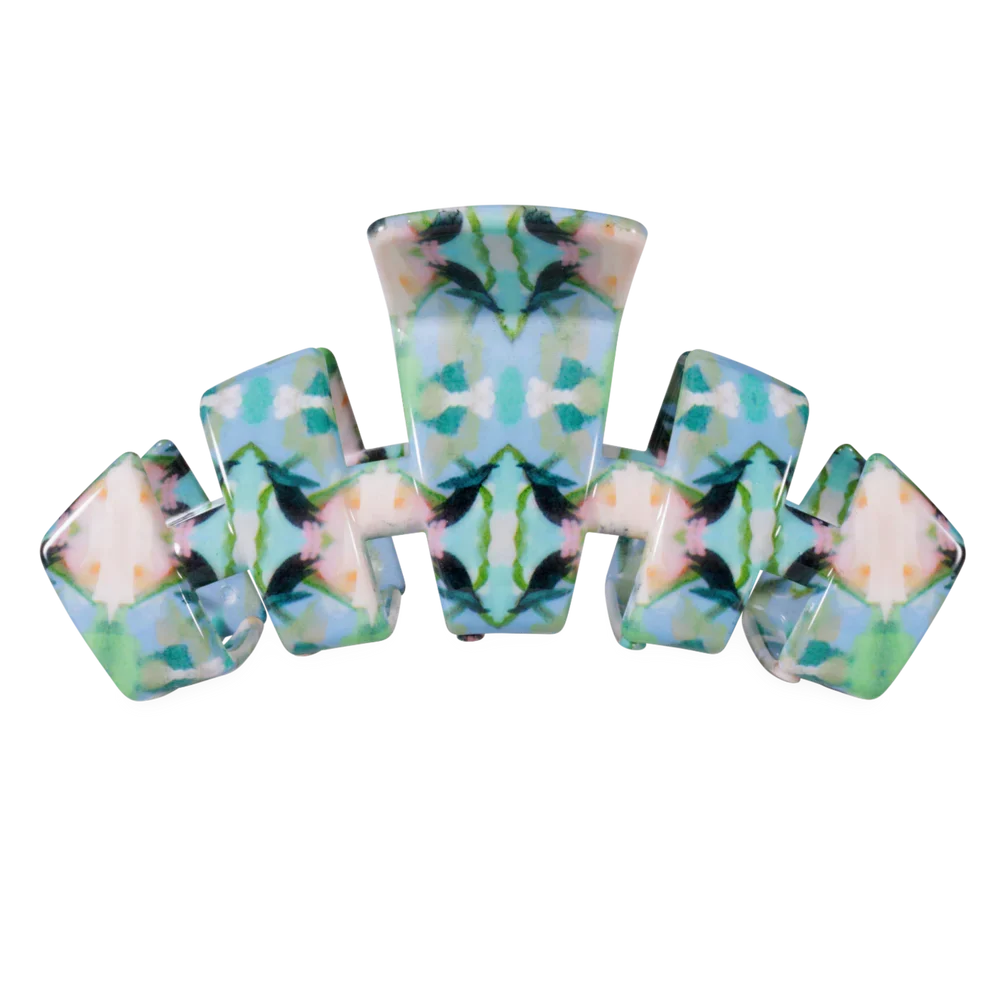 A hair claw clip featuring a symmetrical, kaleidoscopic tie-dye pattern in shades of light blue, mint green, teal, and cream.