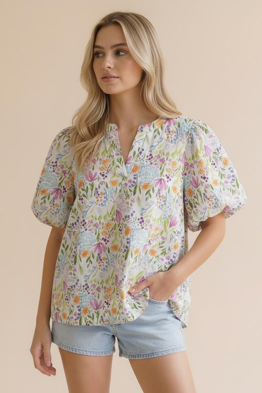 Woman wearing a floral blouse and denim shorts on a beige background
