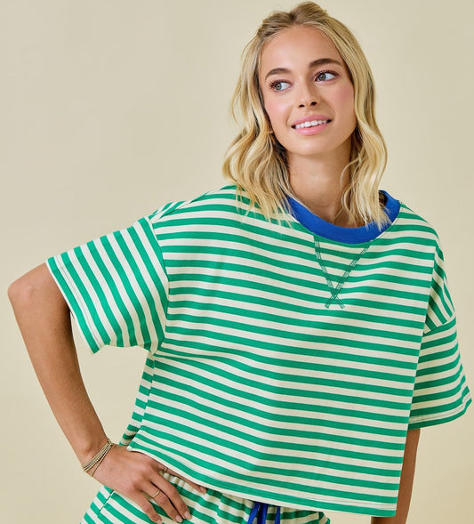Woman wearing a green and white striped outfit with blue accents on a beige background