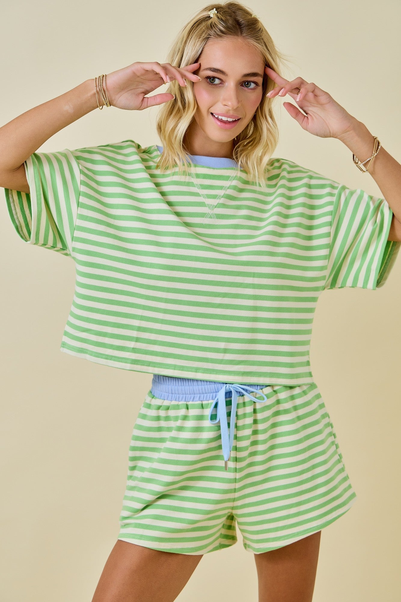 Woman wearing a green and white striped outfit on a beige background