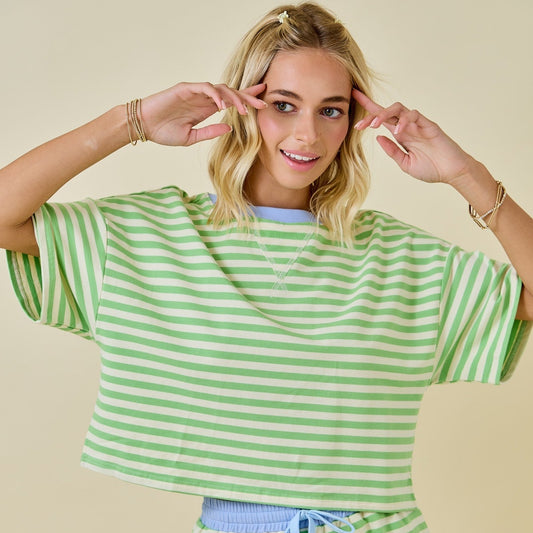 Woman wearing a green and white striped outfit on a beige background