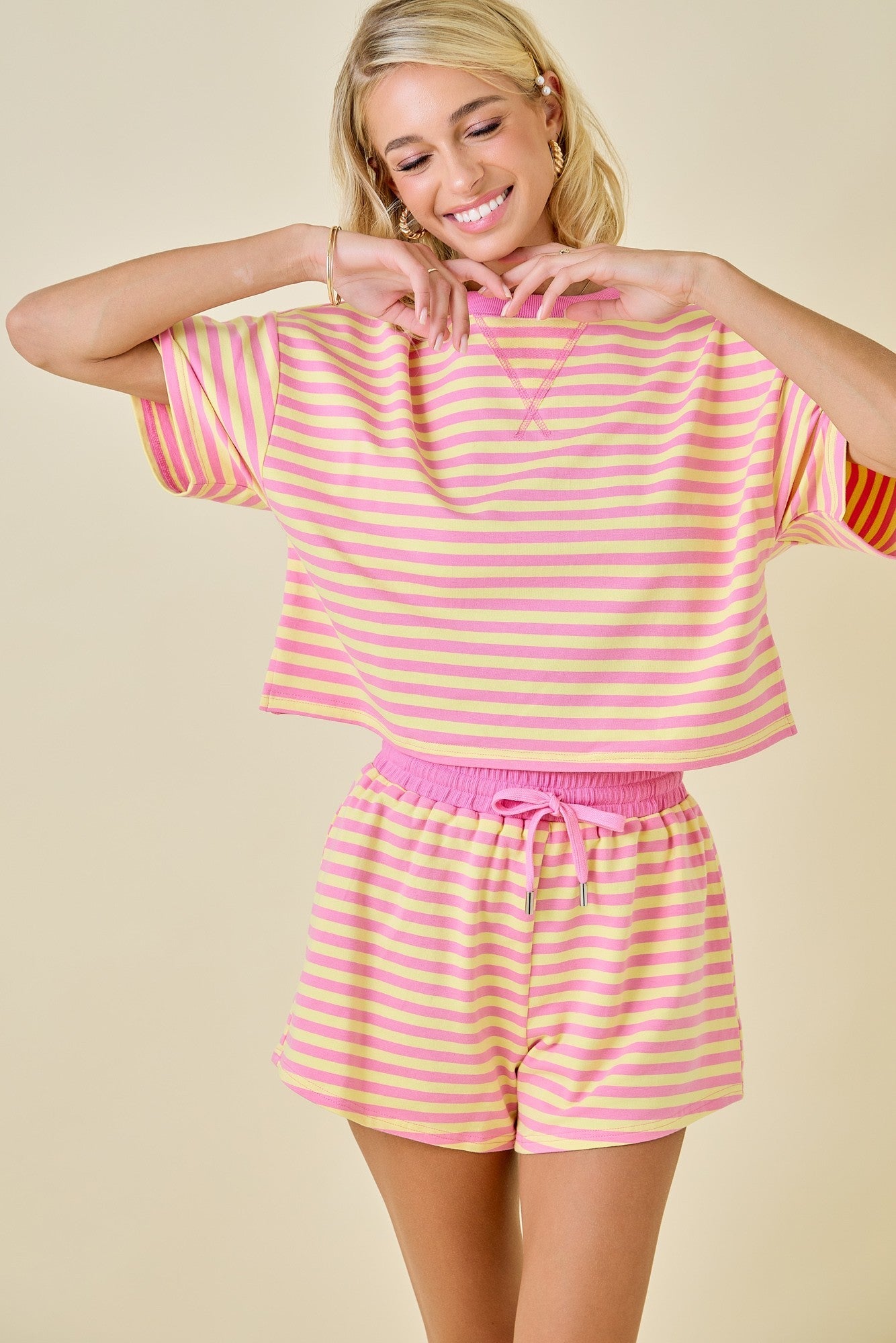 Woman wearing a pink and yellow striped outfit on a beige background