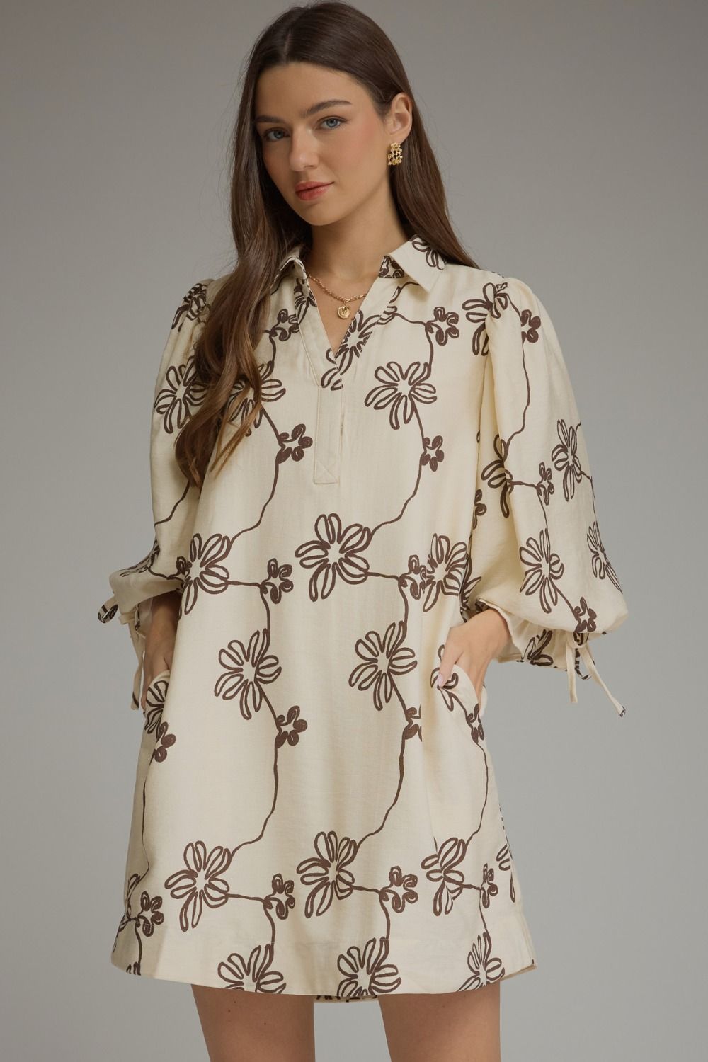Entro-Floral ¾ balloon sleeve mini dress featuring a split neckline and adjustable tie cuffs. Drawstring waist at back. Side pockets.
