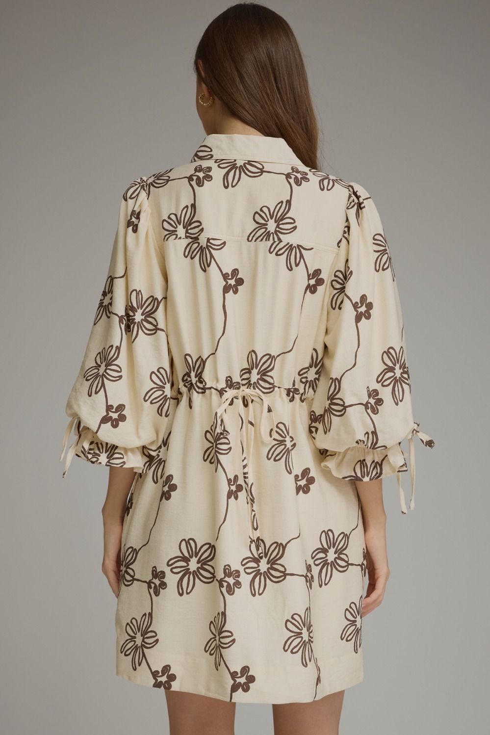 Entro-Floral ¾ balloon sleeve mini dress featuring a split neckline and adjustable tie cuffs. Drawstring waist at back. Side pockets.