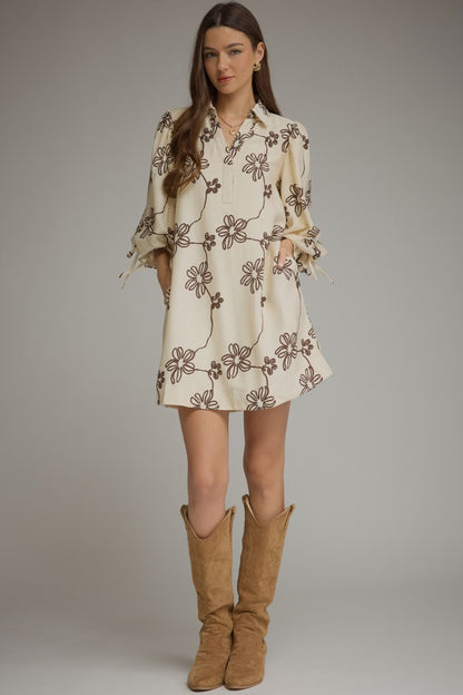 Entro-Floral ¾ balloon sleeve mini dress featuring a split neckline and adjustable tie cuffs. Drawstring waist at back. Side pockets.