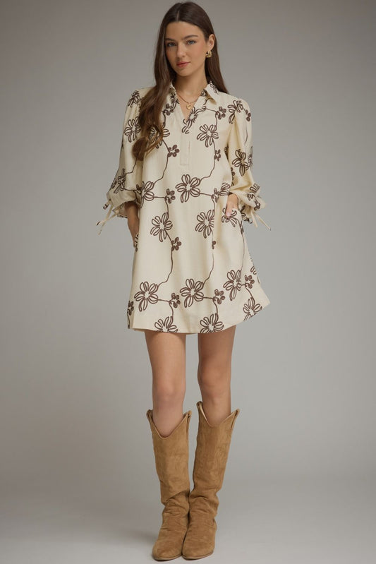 Entro-Floral ¾ balloon sleeve mini dress featuring a split neckline and adjustable tie cuffs. Drawstring waist at back. Side pockets.