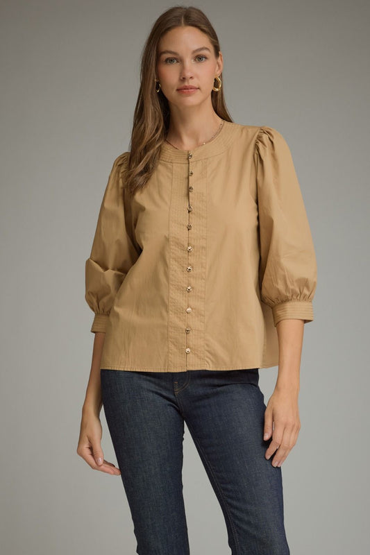Entro-Solid ¾ balloon sleeve top with a round neckline. Button closure at front. Pintuck detail at neckline, front, and sleeve cuffs. Gathered detail at shoulders and back.