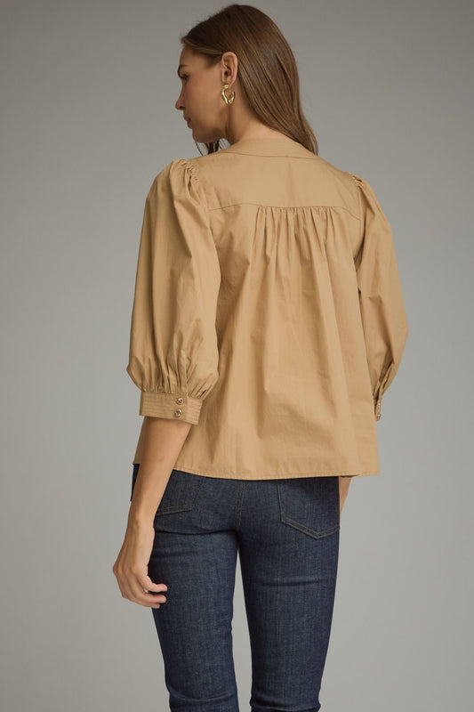 Entro-Solid ¾ balloon sleeve top with a round neckline. Button closure at front. Pintuck detail at neckline, front, and sleeve cuffs. Gathered detail at shoulders and back.
