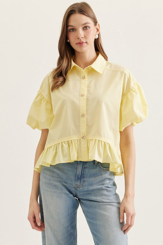Entro Solid short puff sleeve top featuring ruffle hem detail. Button closure at front.