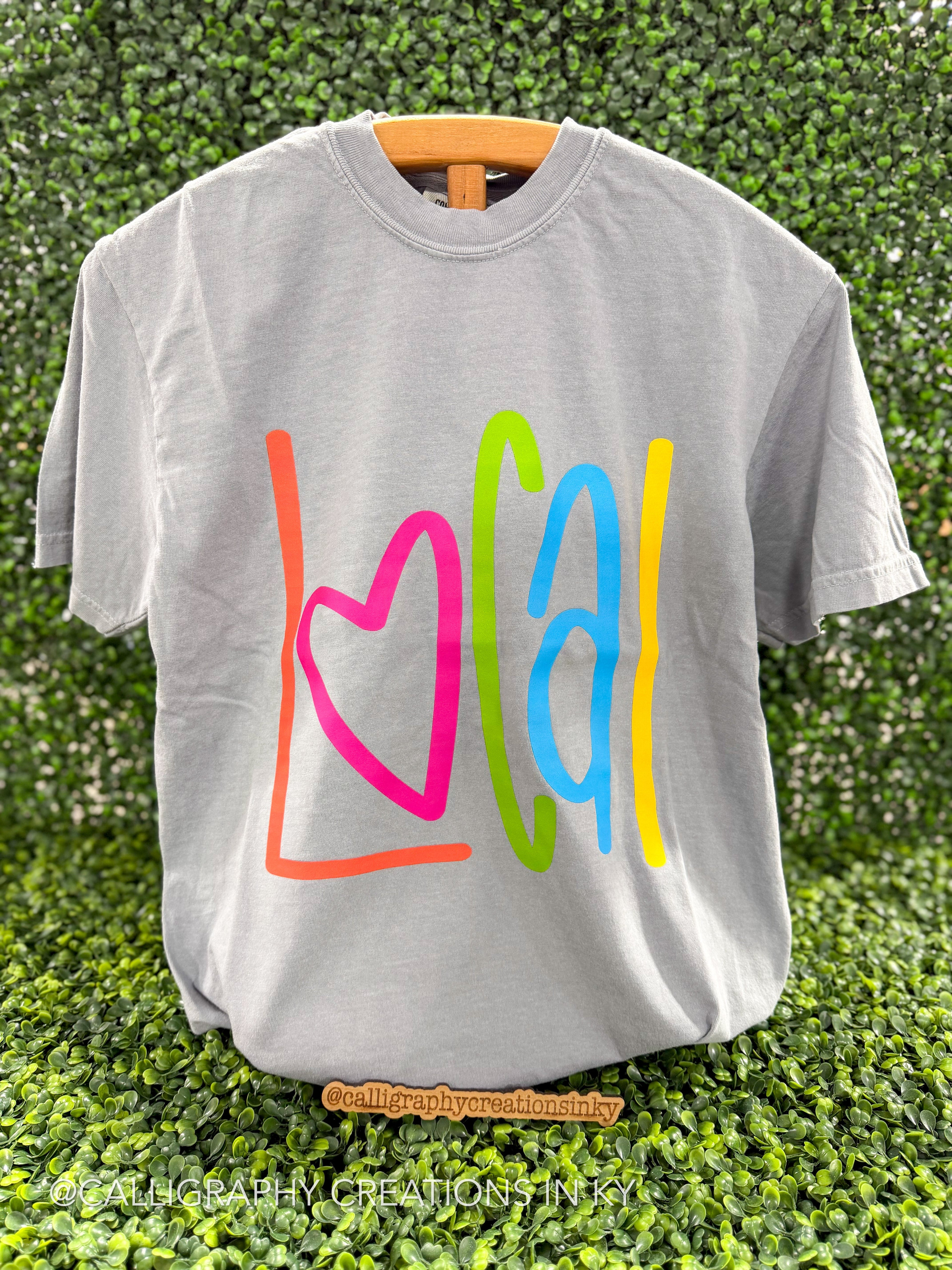Gray shirt with colorful letters spelling out ‘Local’ on a wooden stand