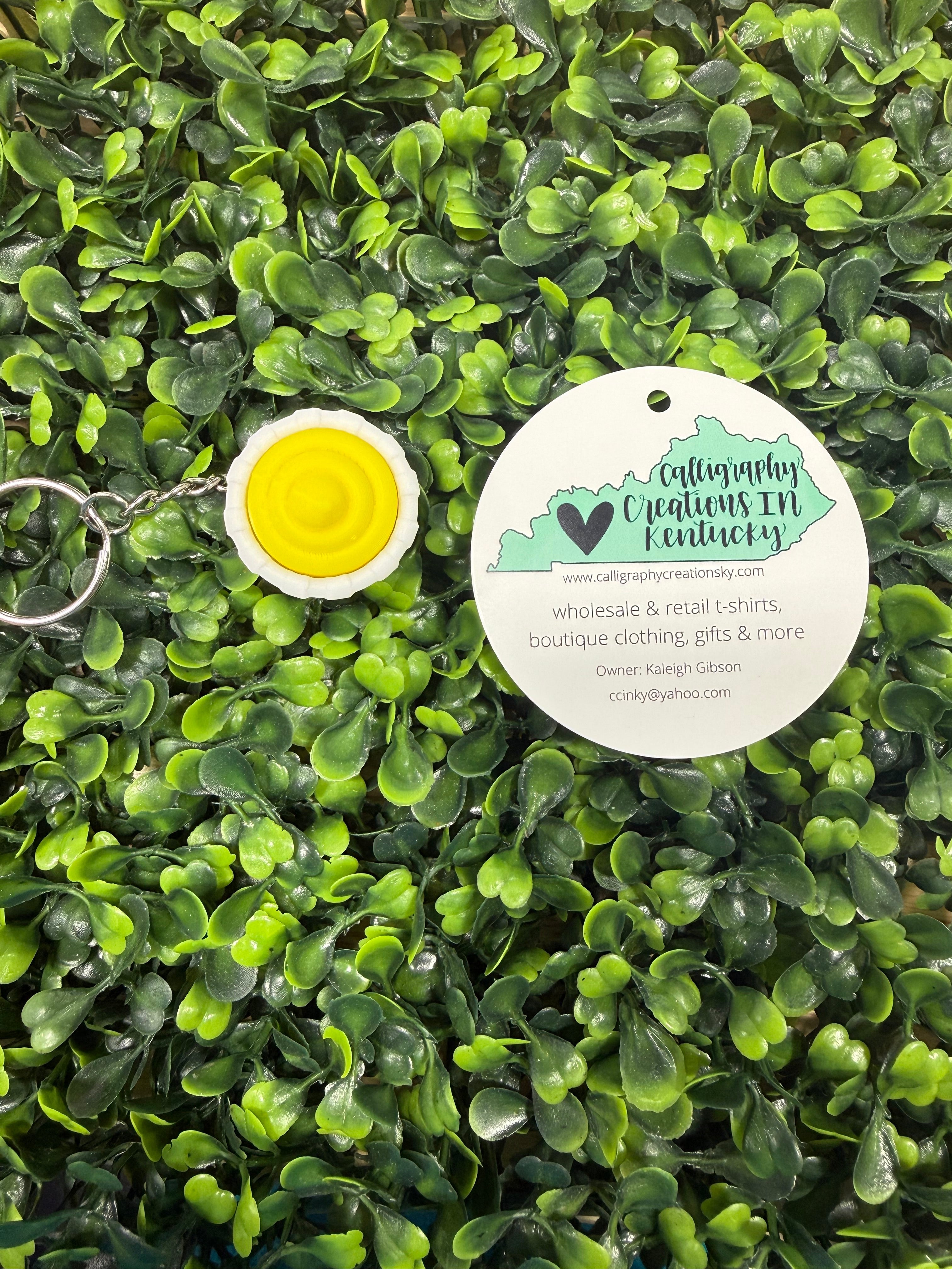 Keychain with yellow center and white border on green leafy background