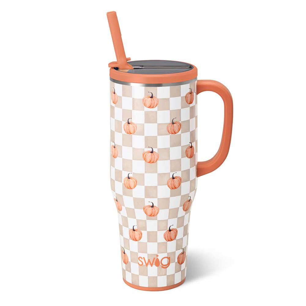 A tall insulated travel tumbler with a handle and straw, featuring an orange and beige checkerboard pattern with small pumpkin illustrations. The tumbler has a dark gray lid and a visible 'swig' logo near the bottom.