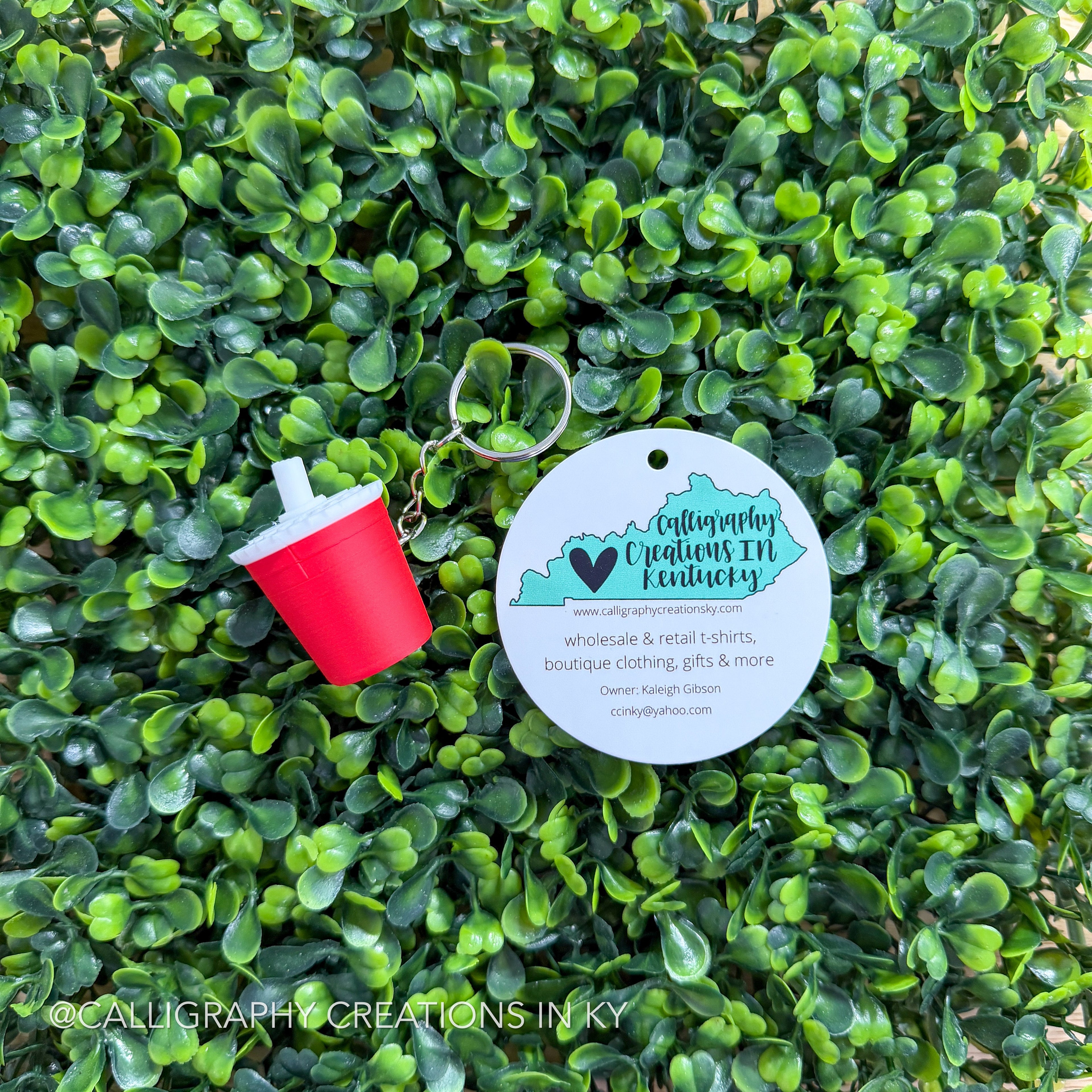 Red drink fidget keychain on greenery background with Calligraphy Creations branding