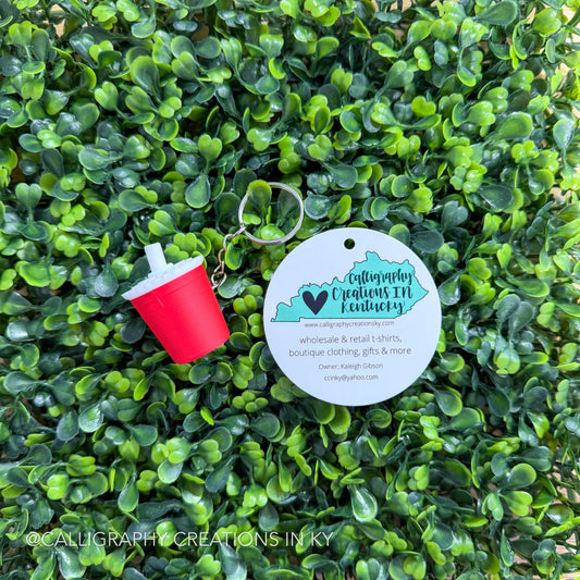 Red drink fidget keychain on greenery background with Calligraphy Creations branding