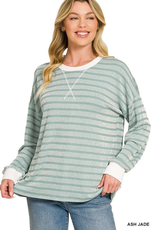 A woman wearing a light green and white striped long-sleeve knit top with white ribbed trim at the crew neck, cuffs, and hem, paired with blue jeans. The text 'ASH JADE' is visible in the bottom right corner.