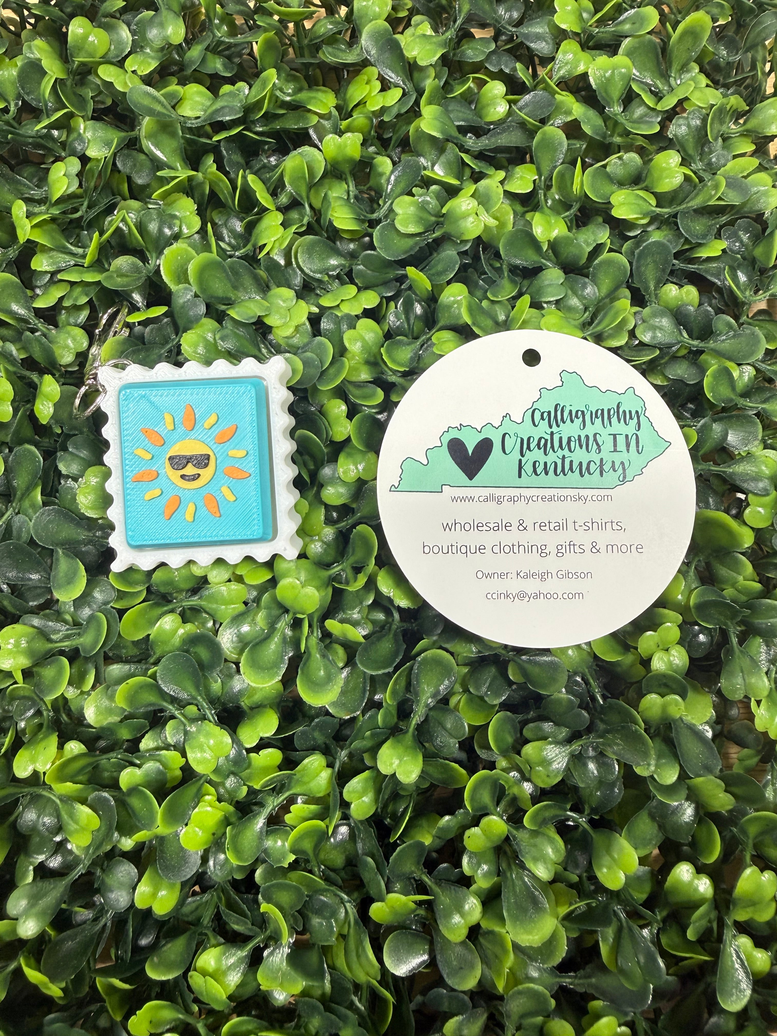 Sun stamp keychain on a green leafy background
