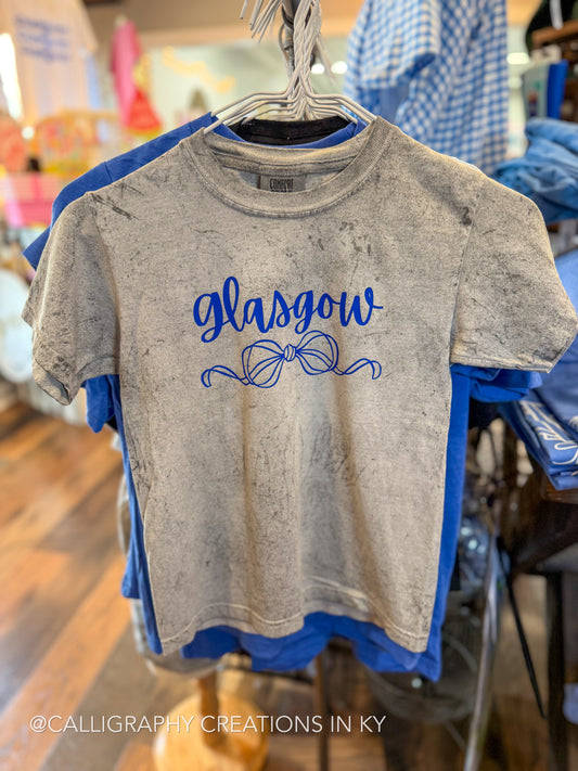 A gray mineral-wash t-shirt with blue 'Glasgow' script and ribbon graphics, hanging on a metal hanger in a retail store.