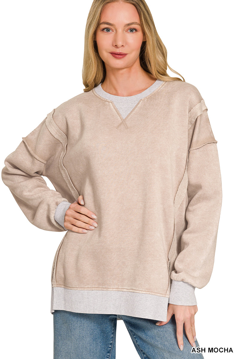 Woman wearing a ash mocha sweater with white trim on a plain background