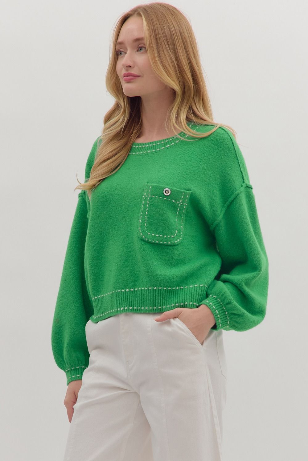 “Close-up of contrast blanket stitch detail on solid sweater knit top. Button chest pocket adds functional style.”